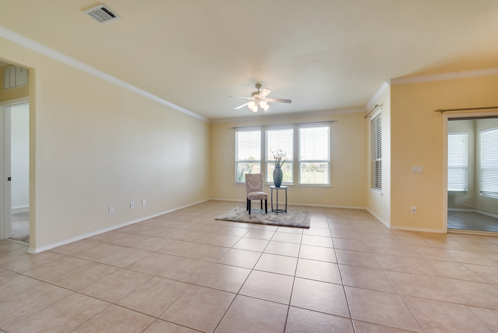    Family Room has Tile Floors Wall of Windows Crown Molding and Ceiling Fant 