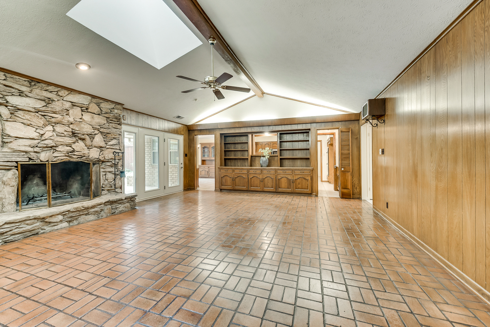    Large Family Room with Stone Fireplace  Beamed Ceiling and Wood Paneling and Wall of Built Ins 